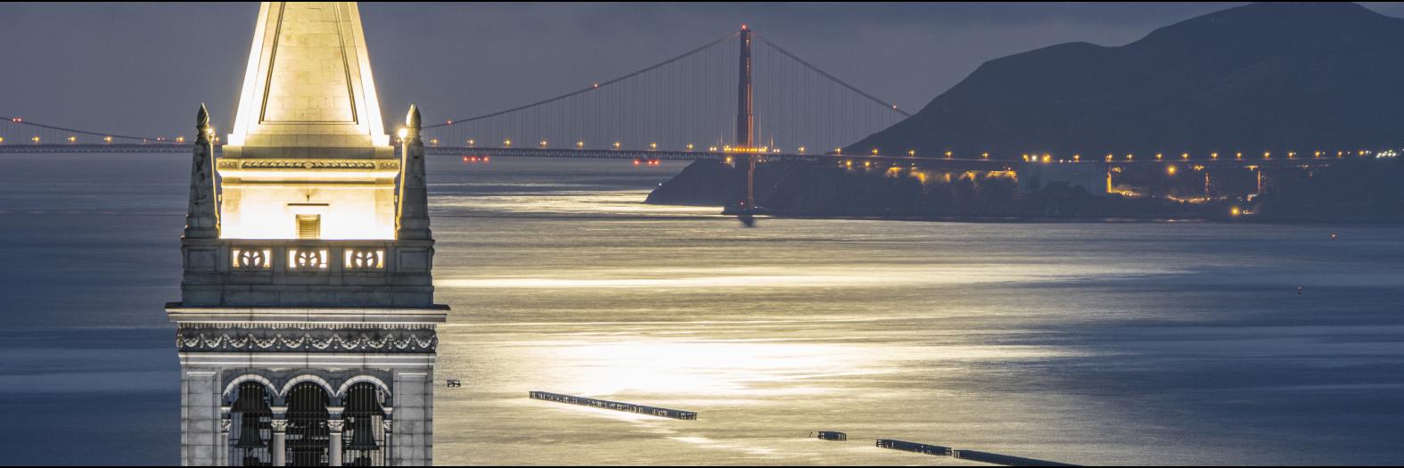 Photo of the Golden Gate Bridge at night, with Berkeley's campanile in the foreground