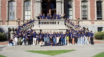 70 students in blue shirts line up to take a picture in front of south hall