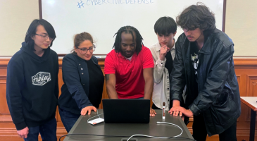 man surrounded by students around a computer