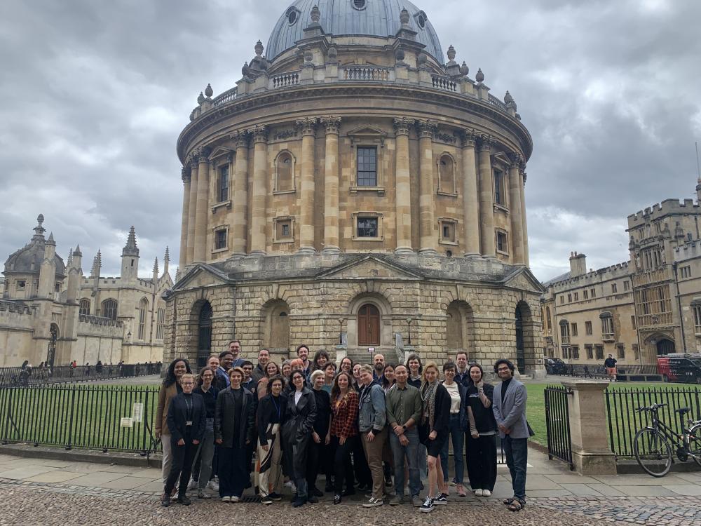 group of graduate students in front of a large round building