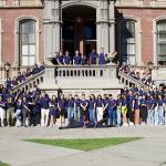 70 students in blue shirts line up to take a picture in front of south hall