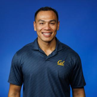 Lit Phansiri facing front wearing a blue Cal collard shirt in front of a blue background