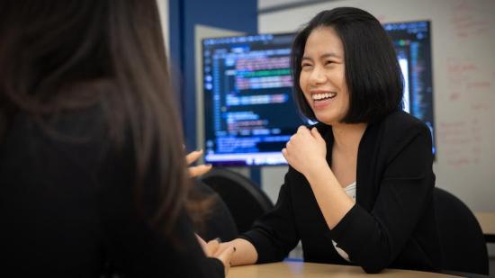 woman smiling in front of screen with code