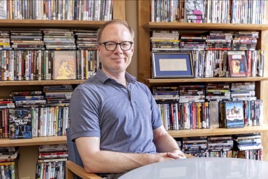 David batman sitting with dvds behind him