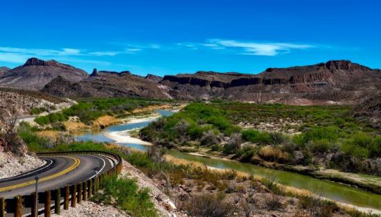 Photo of the rio grande river with mountains in the background on a sunny day. 