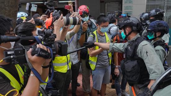 Riot police clear away media gathered in Hong Kong last week ahead of debate on a bill that would criminalize abuse of the Chinese national anthem. (Vincent Yu/AP via NPR)