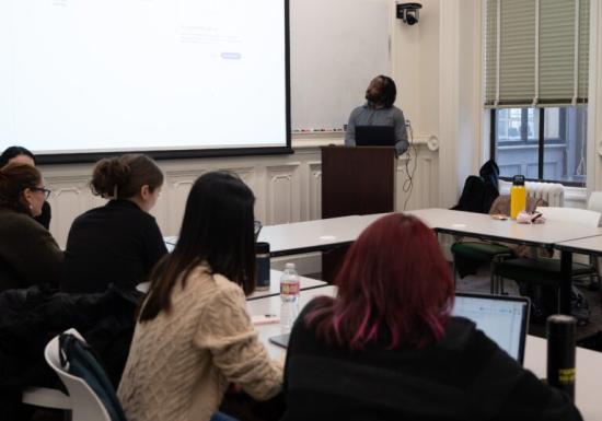 Man teaching to a class, looking at projector screen