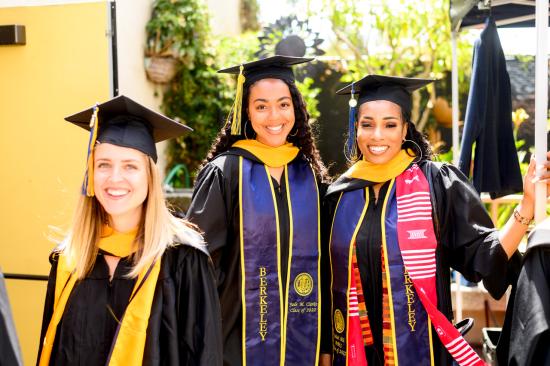 three graduating master's students in regalia