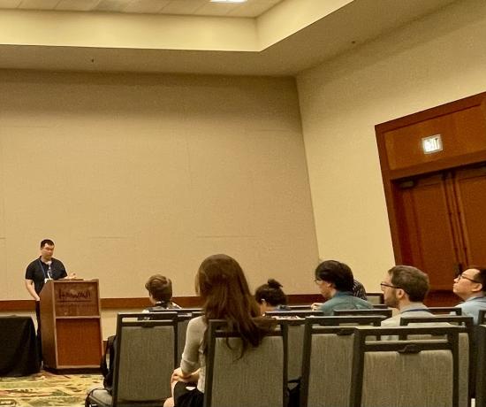 blurry photo of a man in glasses at a lectern