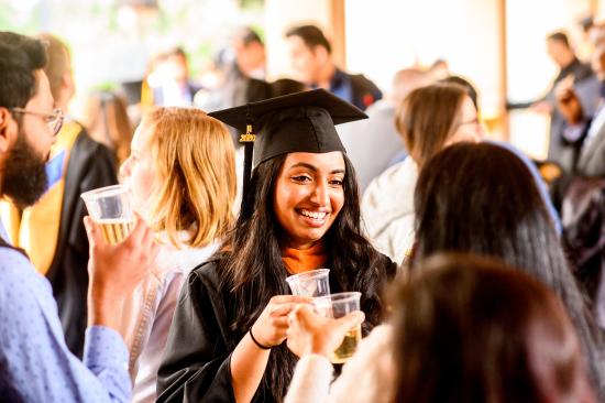 graduate clinks champagne with friends after the ceremony