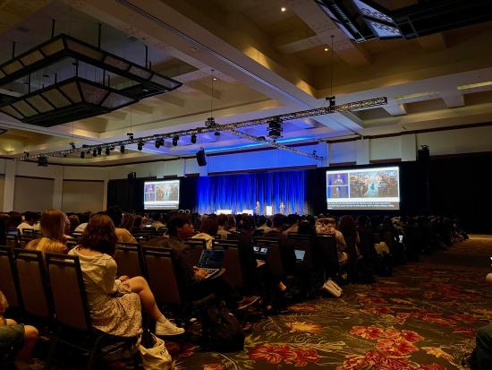 photo of a dark conference hall where someone presents on a screen