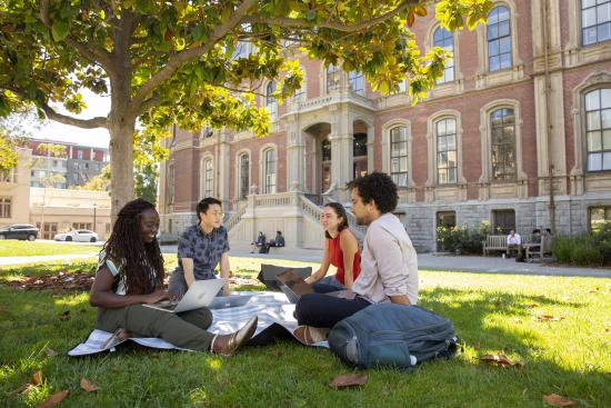 Several students studying together, sitting on the grass in front of South Hall