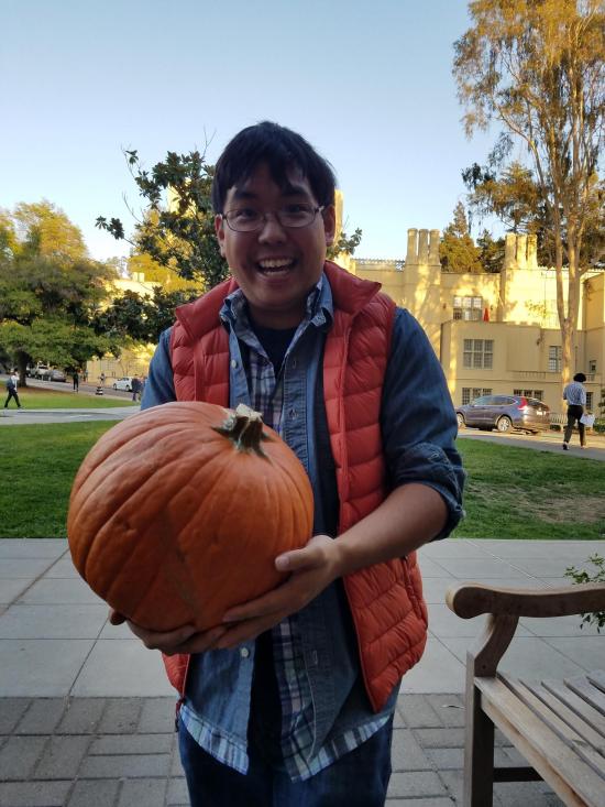 man in orange vest holds a pumpkin